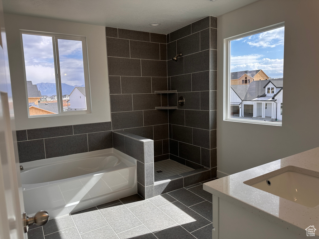 Bathroom featuring a wealth of natural light, vanity, and plus walk in shower