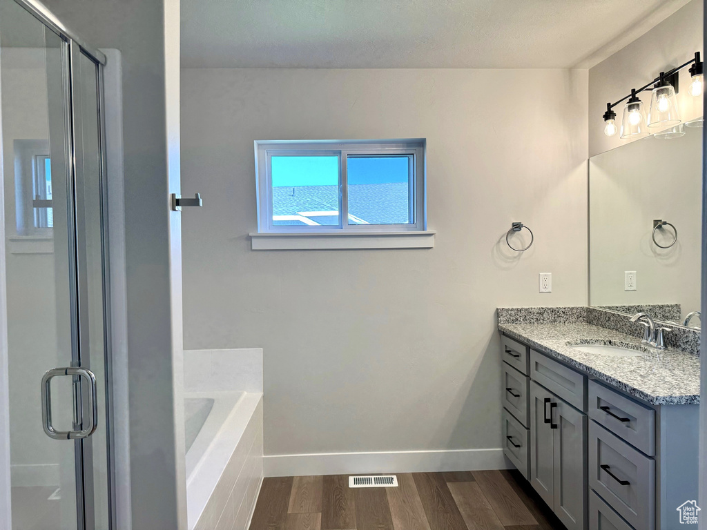 Bathroom featuring shower with separate bathtub, vanity, and hardwood / wood-style floors