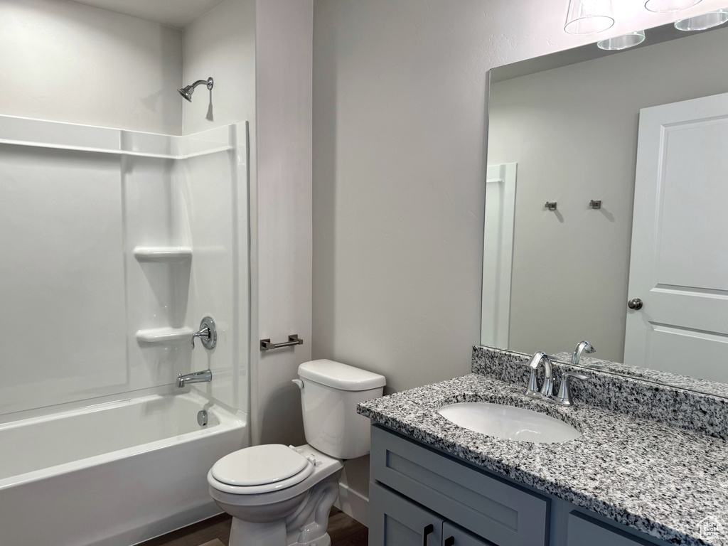 Full bathroom with vanity, shower / bath combination, hardwood / wood-style floors, and toilet