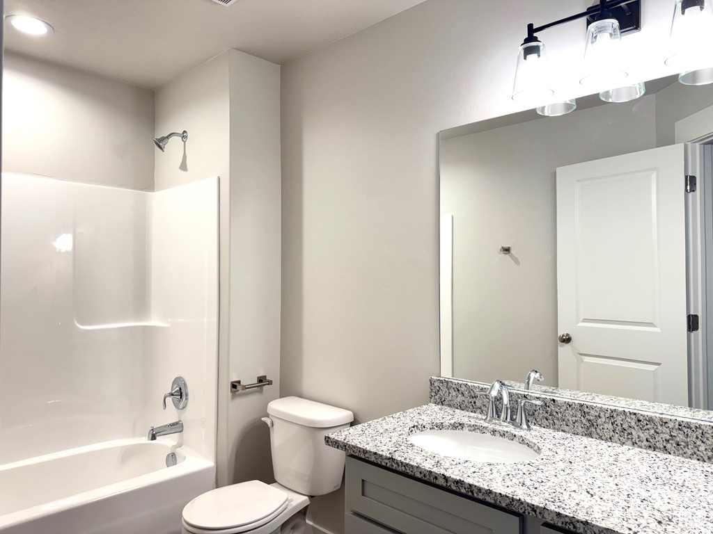 Full bathroom with tub / shower combination, vanity, and toilet