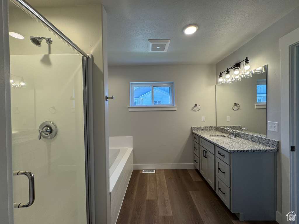 Bathroom featuring a textured ceiling, shower with separate bathtub, vanity, and wood-type flooring