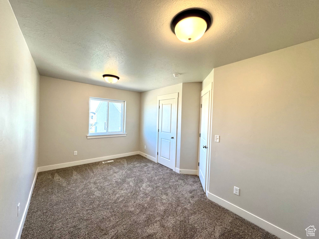 Carpeted empty room featuring a textured ceiling