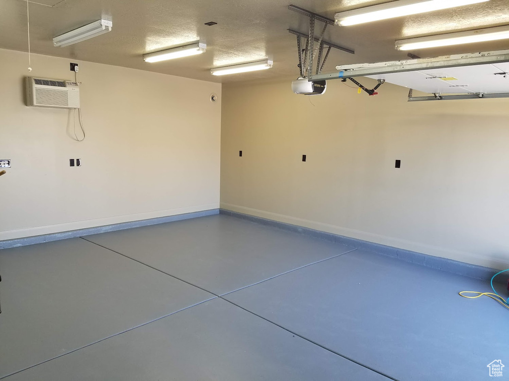 Garage featuring a garage door opener and a wall unit AC