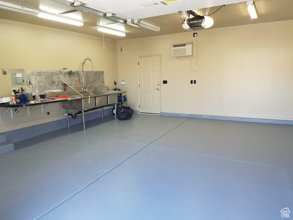 Garage featuring a garage door opener and a wall unit AC