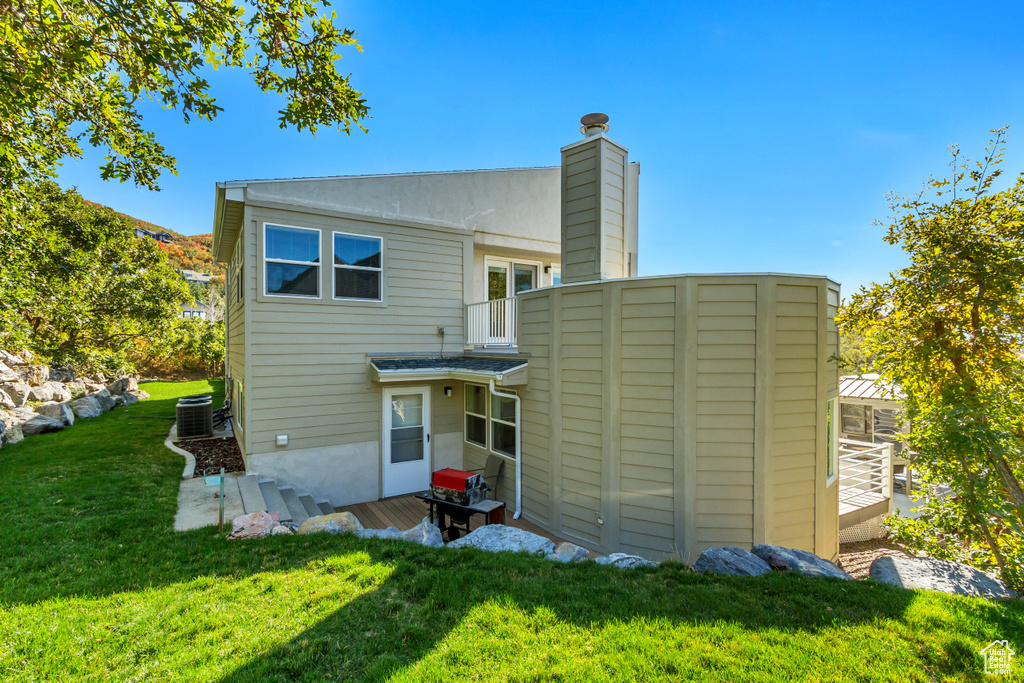 Back of property featuring central AC unit and a lawn