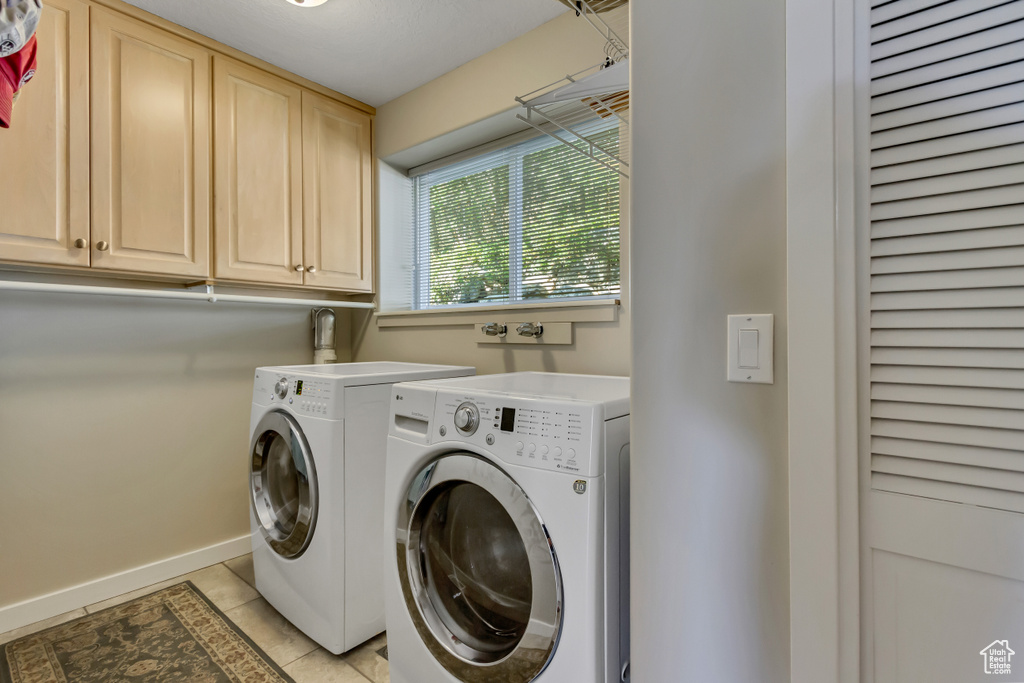 Laundry room featuring light tile patterned flooring, washer and dryer, and cabinets