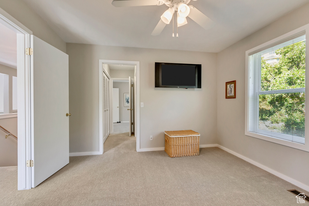 Unfurnished bedroom with light carpet and ceiling fan