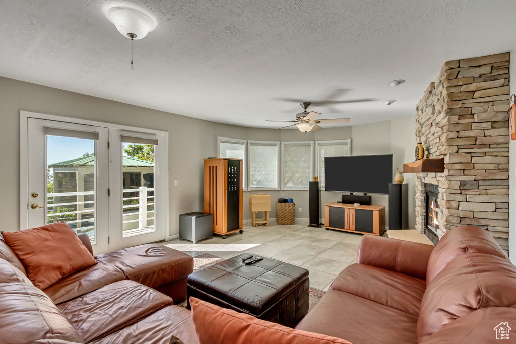 Tiled living room featuring ceiling fan, a textured ceiling, and a fireplace