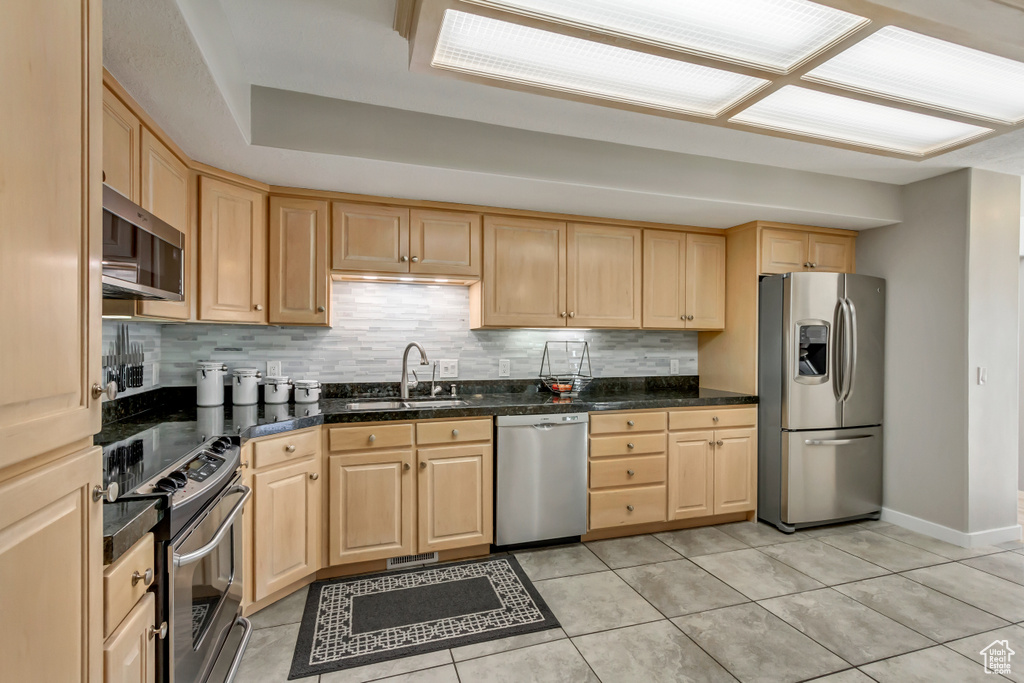 Kitchen featuring light brown cabinets, appliances with stainless steel finishes, backsplash, and sink