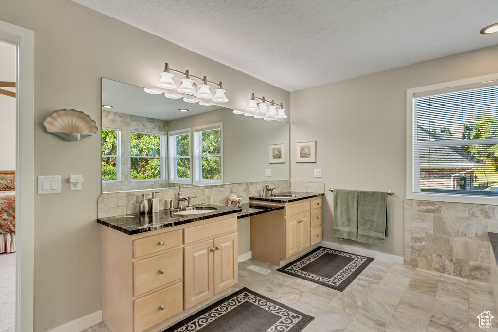 Bathroom featuring vanity, a textured ceiling, and a wealth of natural light