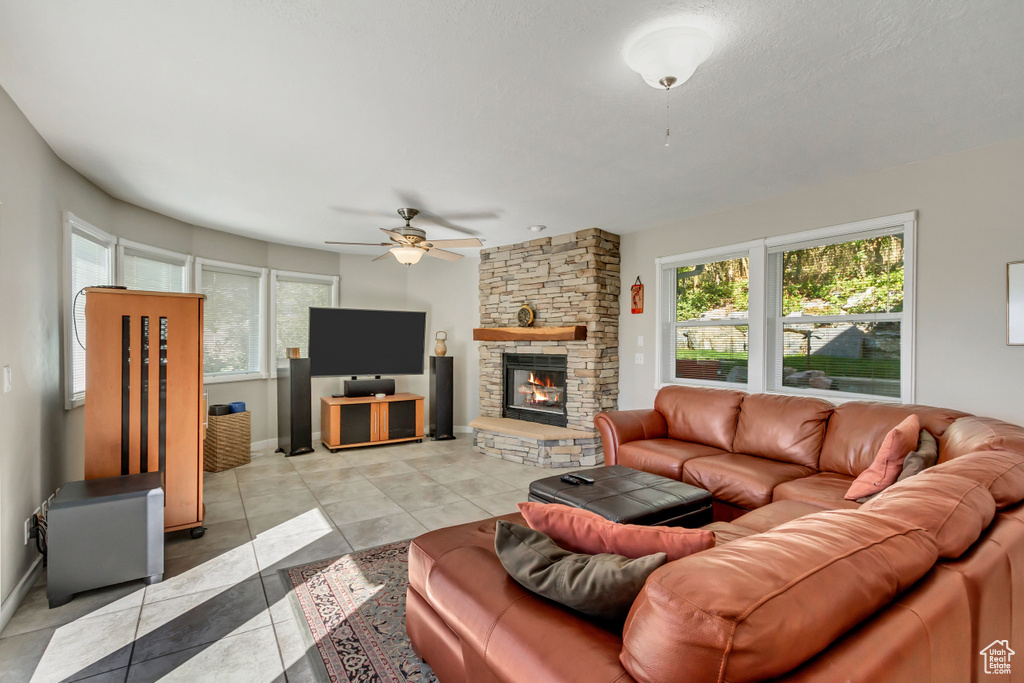 Living room featuring a fireplace, light tile patterned flooring, and ceiling fan