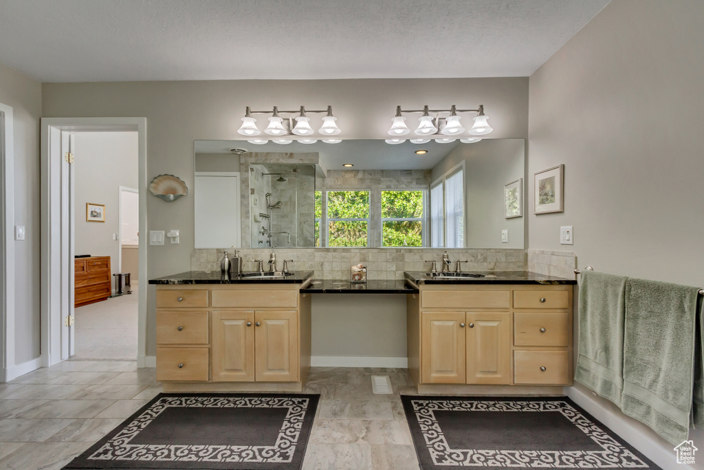 Bathroom featuring vanity, a textured ceiling, tasteful backsplash, and a shower with door