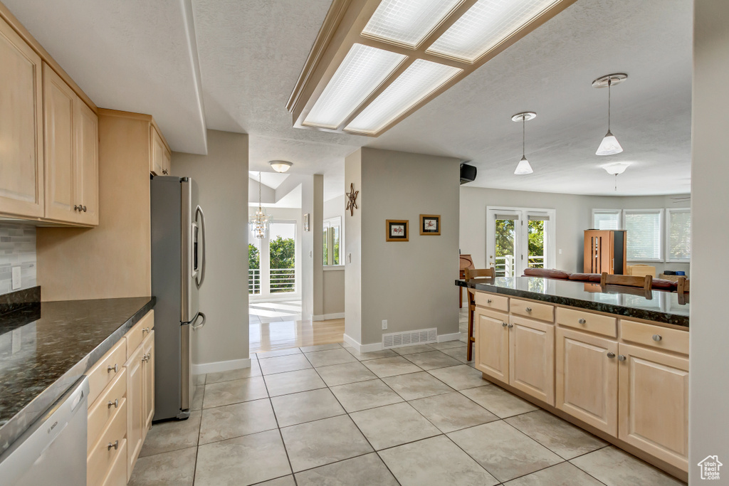 Kitchen featuring dishwasher, light tile patterned flooring, stainless steel refrigerator with ice dispenser, hanging light fixtures, and french doors