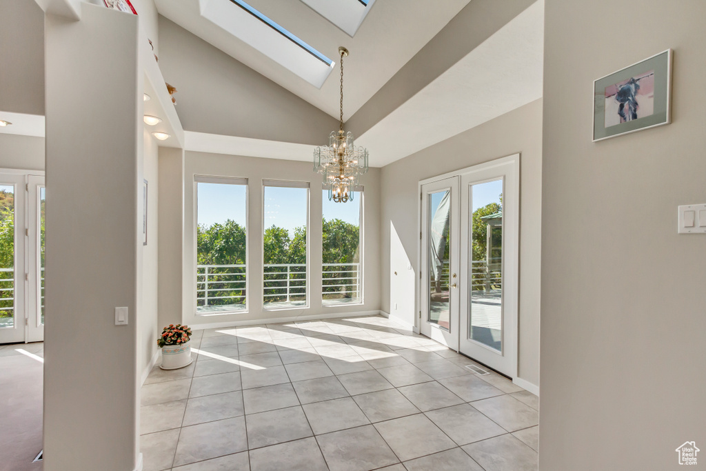 Interior space with a skylight, a notable chandelier, high vaulted ceiling, and a wealth of natural light