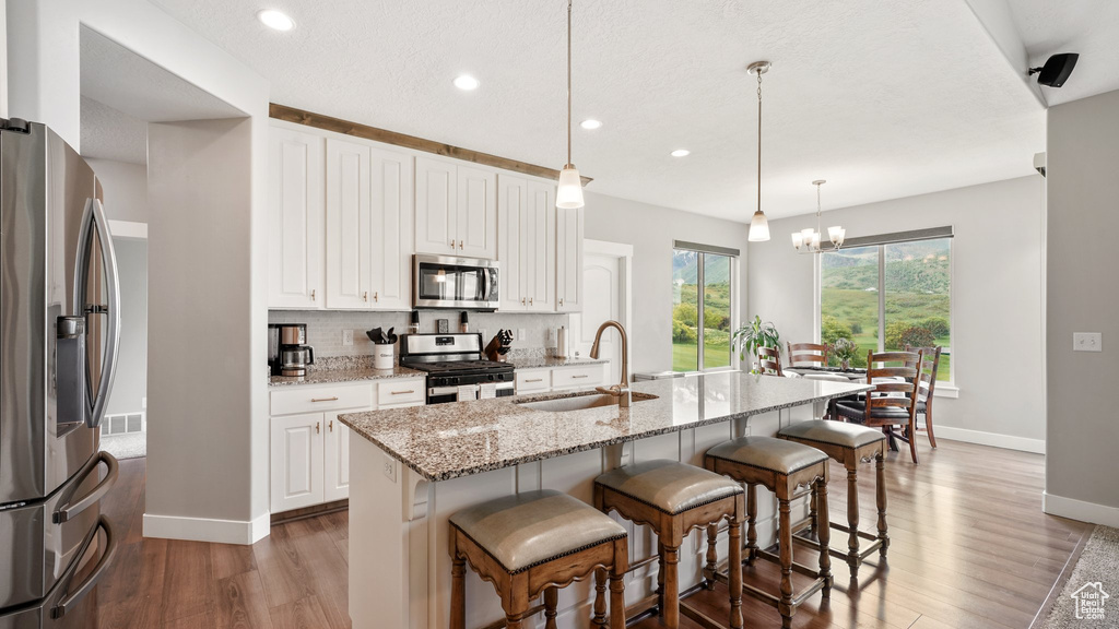 Kitchen featuring appliances with stainless steel finishes, baseboards, a sink, light wood-style floors, and backsplash