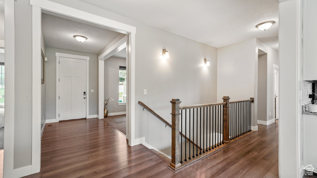 Hallway with an upstairs landing, wood finished floors, and baseboards
