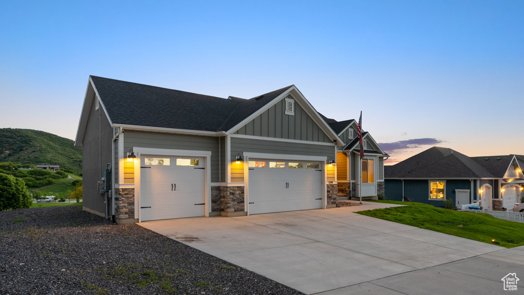 Craftsman inspired home with an attached garage, board and batten siding, stone siding, concrete driveway, and a shingled roof