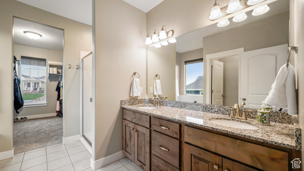 Full bathroom with a stall shower, tile patterned floors, double vanity, and baseboards
