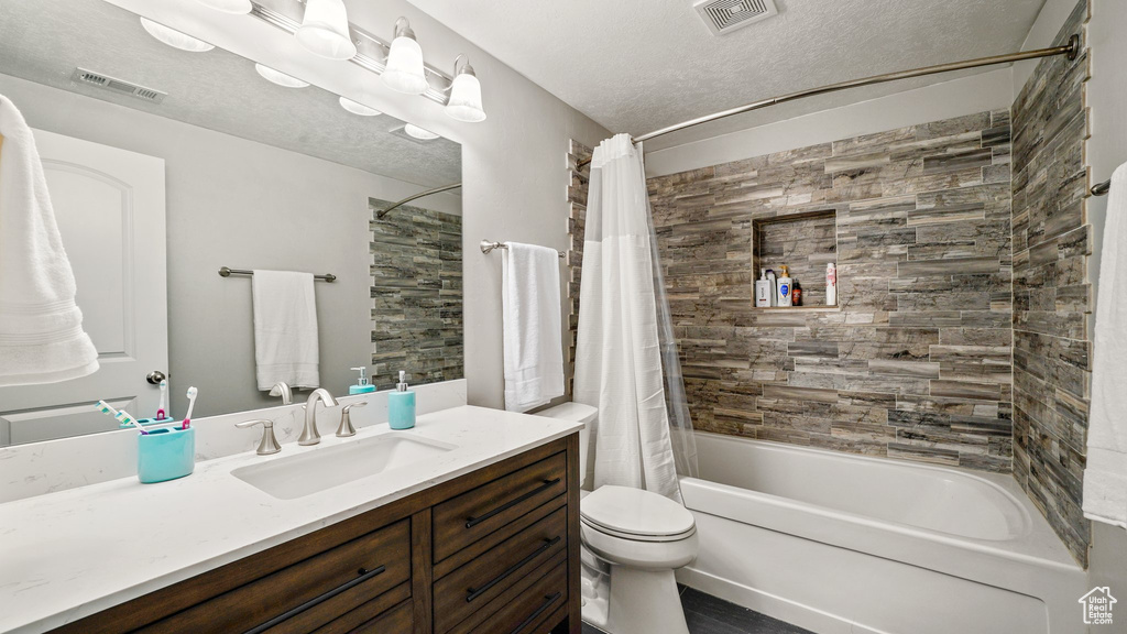 Full bathroom featuring shower / bathtub combination with curtain, toilet, and vanity