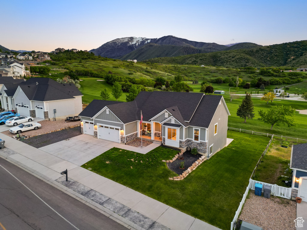 View of front of house with an attached garage, stone siding, board and batten siding, driveway, and a mountain view