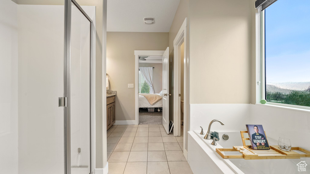 Ensuite bathroom featuring a bath, a stall shower, tile patterned floors, vanity, and baseboards