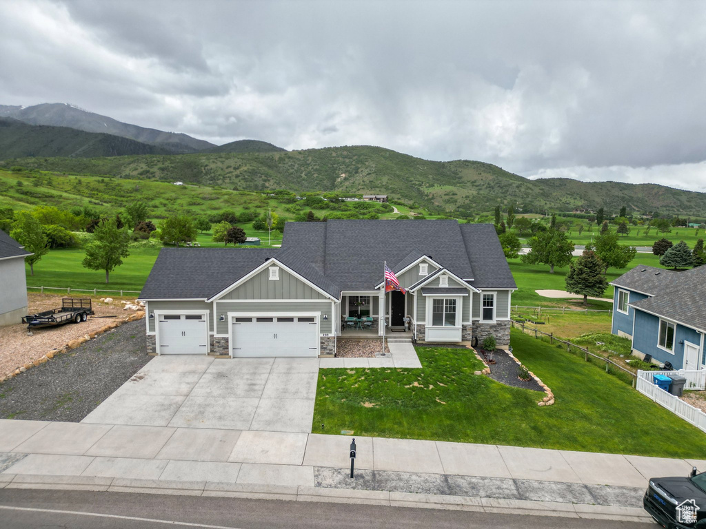 Craftsman-style house with stone siding, board and batten siding, an attached garage, concrete driveway, and a mountain view