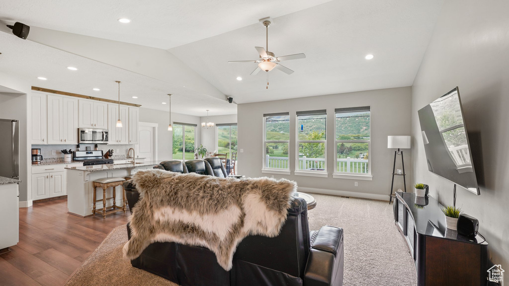Living room featuring vaulted ceiling, a ceiling fan, recessed lighting, wood finished floors, and baseboards