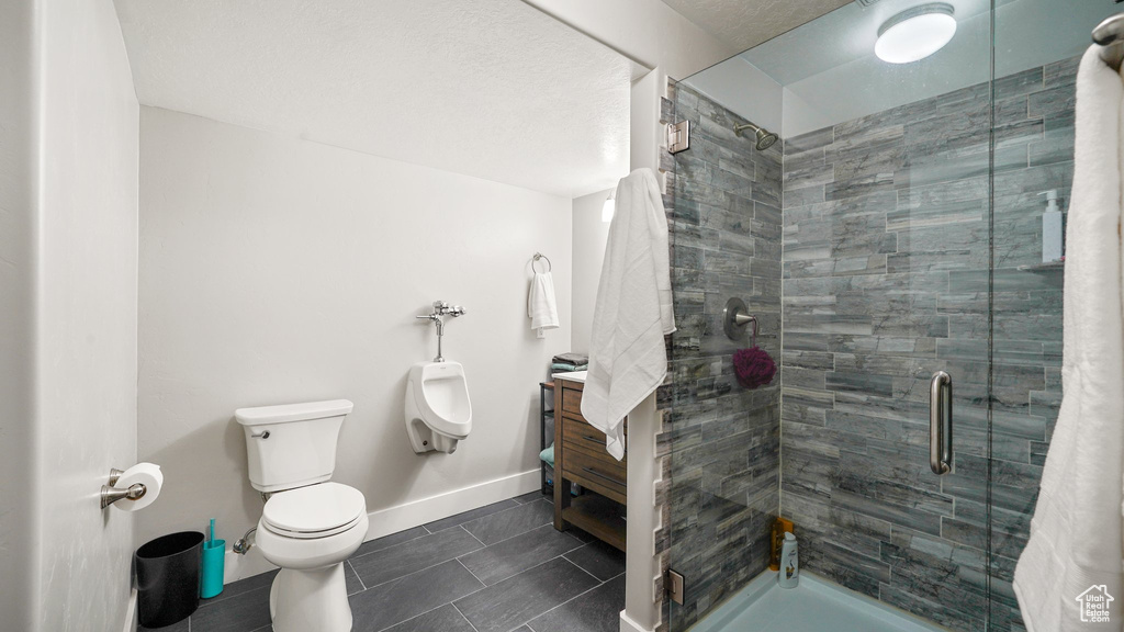 Bathroom featuring a shower stall, tile patterned flooring, baseboards, and toilet