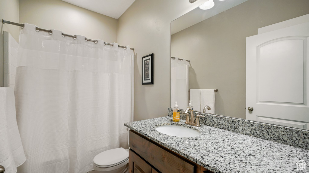 Bathroom featuring toilet, vanity, and curtained shower