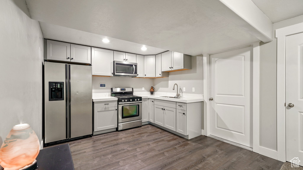 Kitchen featuring stainless steel appliances, a sink, dark wood-type flooring, light countertops, and recessed lighting