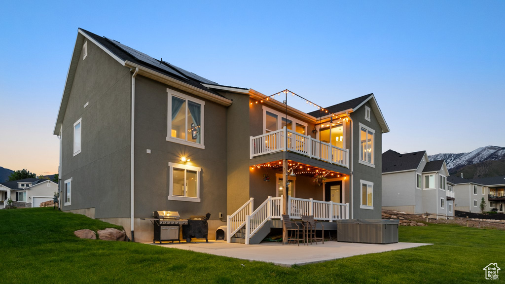 Rear view of property featuring a balcony, a patio area, stucco siding, and a yard