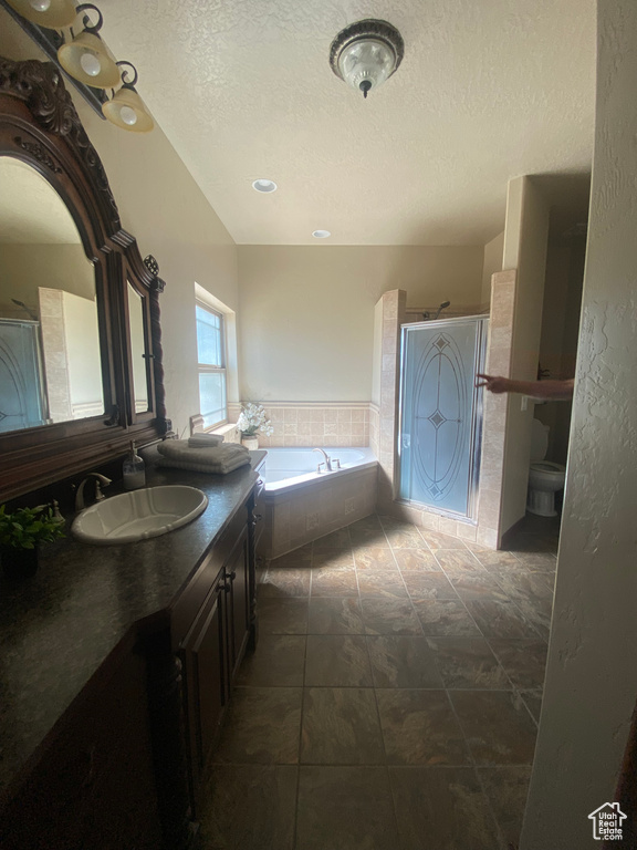 Bathroom featuring vanity, tile patterned flooring, a textured ceiling, and a relaxing tiled tub