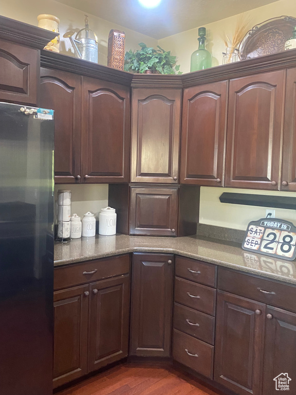 Kitchen with refrigerator, dark brown cabinets, and dark wood-type flooring