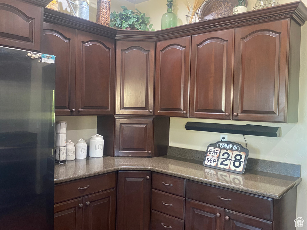 Kitchen with dark brown cabinets and black fridge