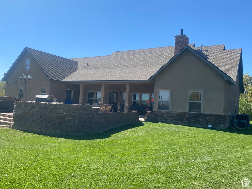 Rear view of house featuring central AC unit, a yard, and a patio area