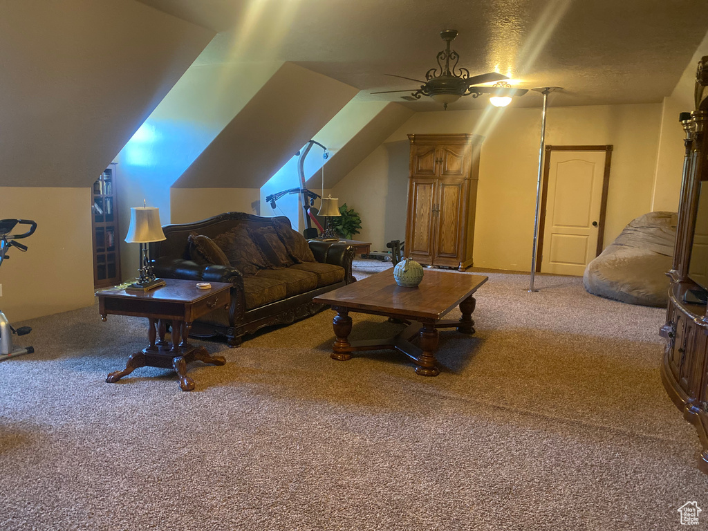 Carpeted living room featuring ceiling fan and vaulted ceiling