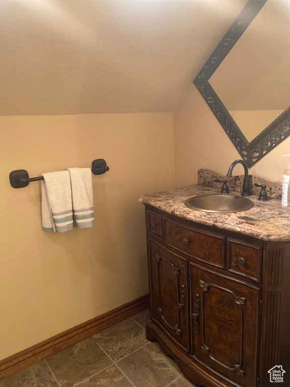 Bathroom with vaulted ceiling, vanity, and tile patterned floors