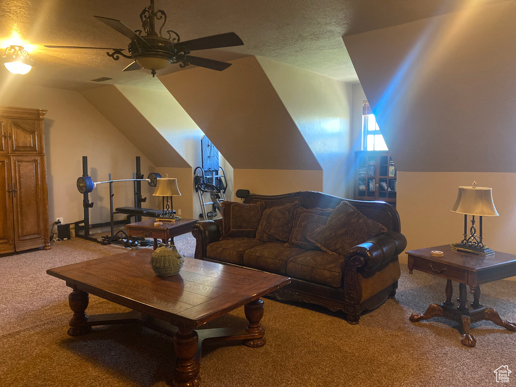 Carpeted living room with lofted ceiling, a textured ceiling, and ceiling fan