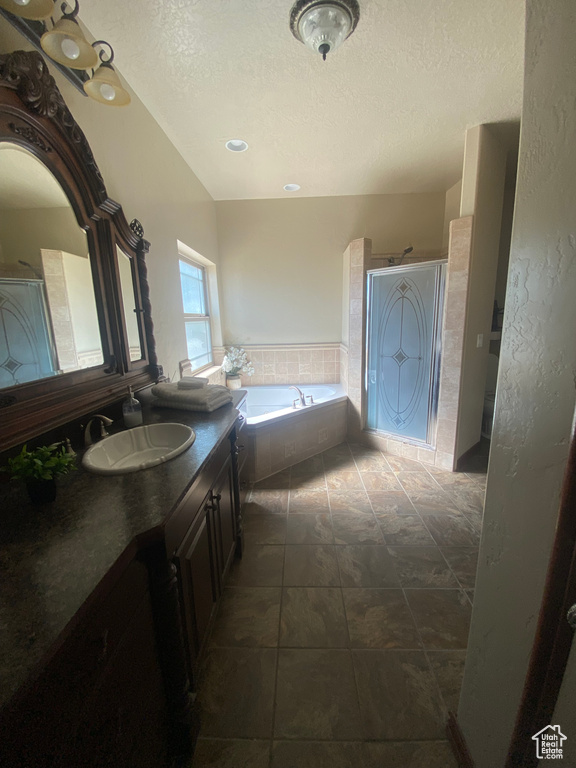 Bathroom featuring vanity, plus walk in shower, tile patterned flooring, and a textured ceiling