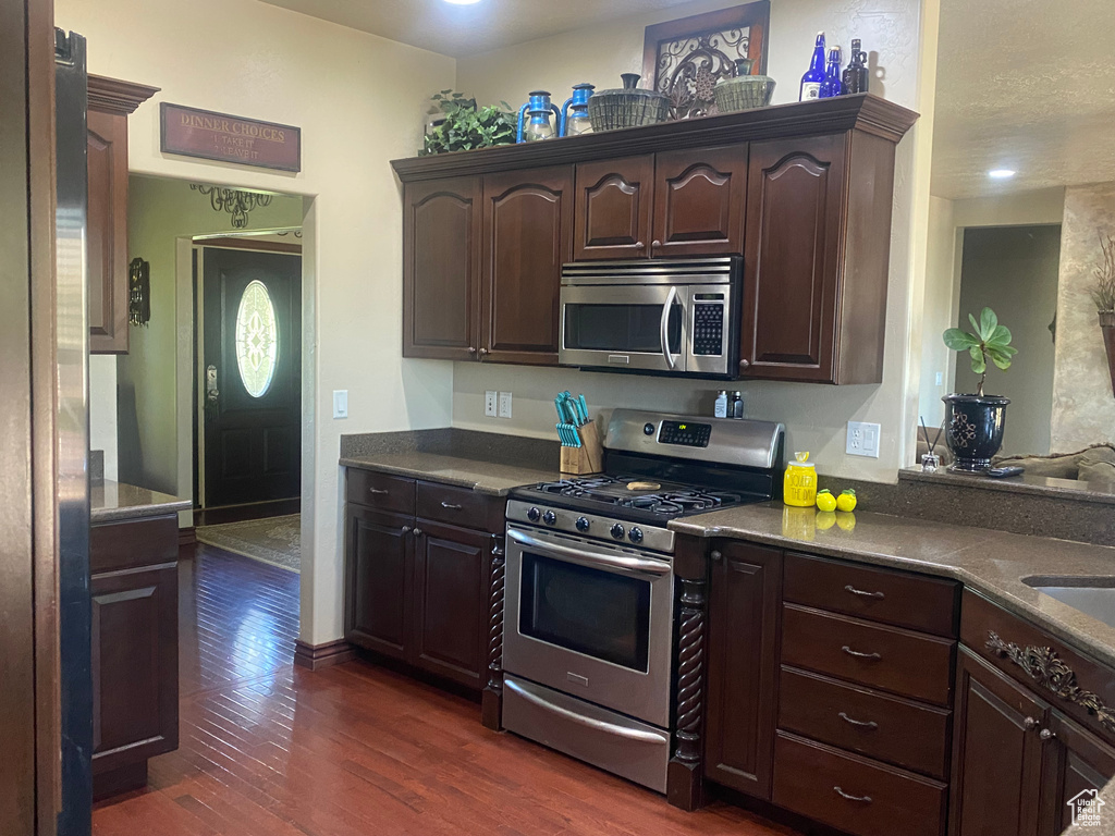 Kitchen with dark brown cabinets, stainless steel appliances, and dark hardwood / wood-style floors