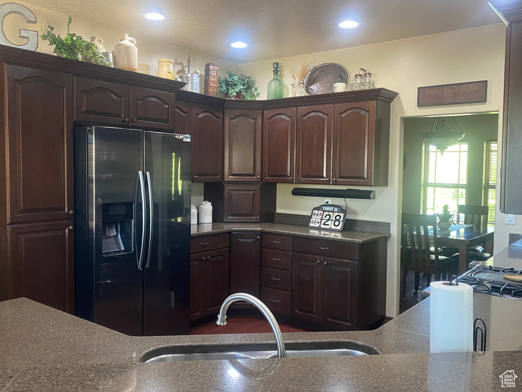 Kitchen with sink, dark brown cabinetry, and stainless steel fridge