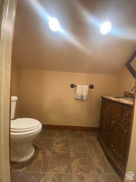 Bathroom with lofted ceiling, vanity, and toilet