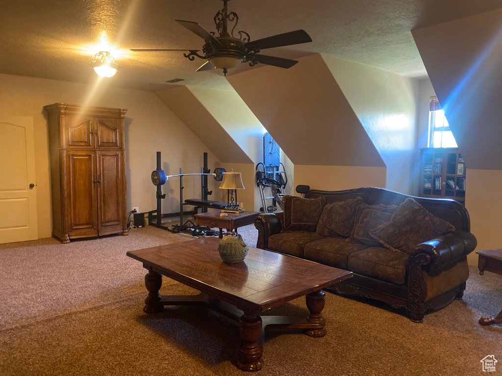 Carpeted living room with a textured ceiling, lofted ceiling, and ceiling fan