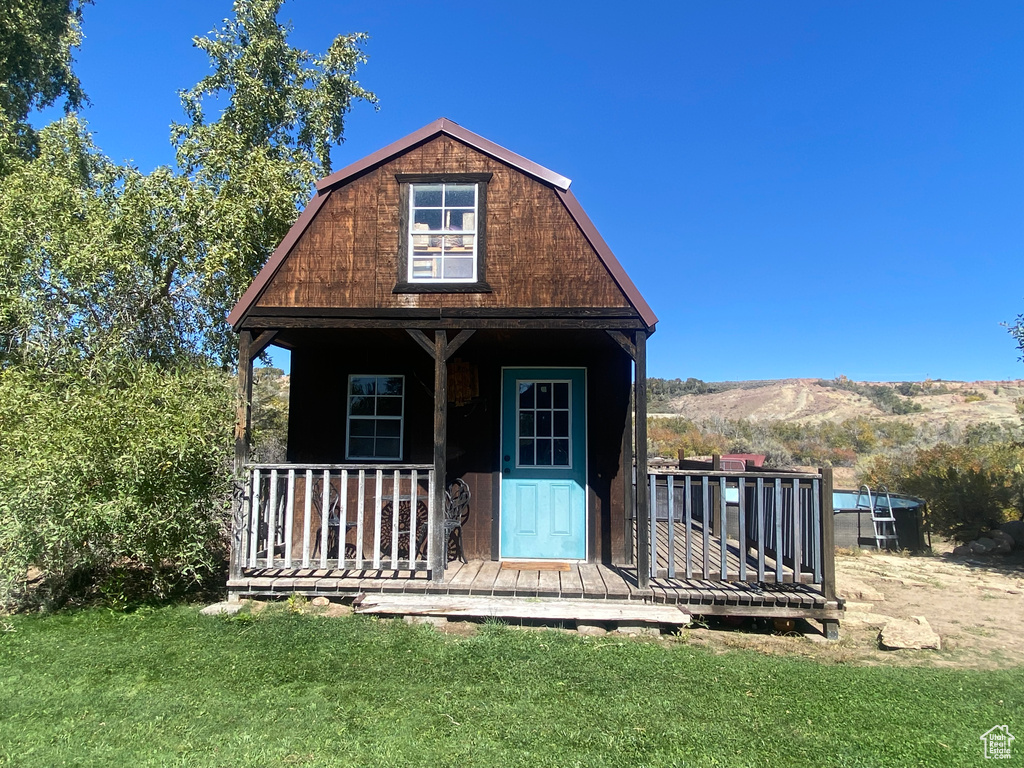 View of front facade with a mountain view, a front lawn, and a porch