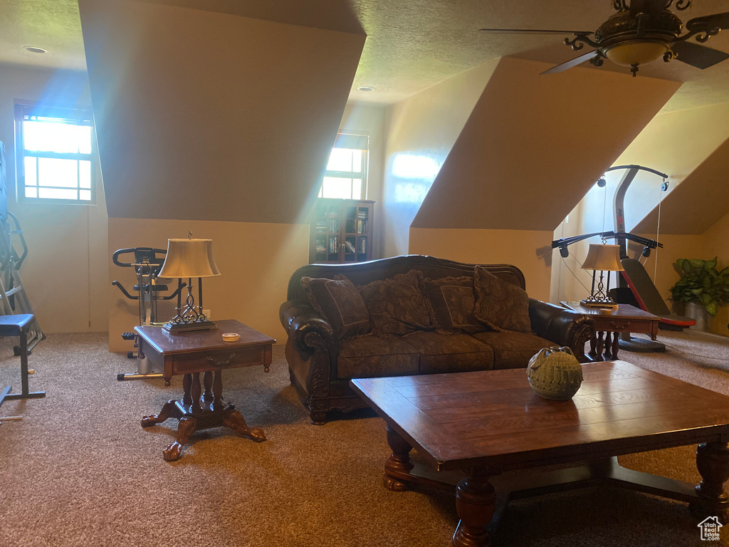 Living room featuring carpet flooring, lofted ceiling, a textured ceiling, and ceiling fan