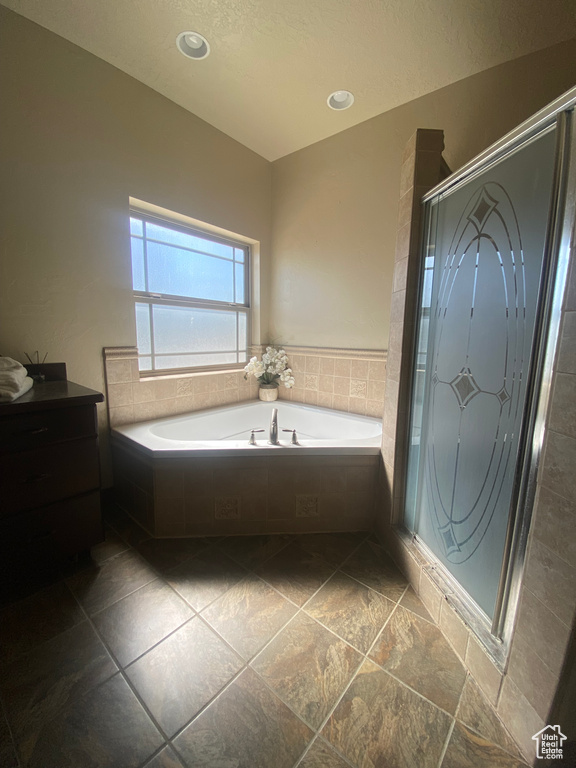 Bathroom featuring tile patterned floors, vanity, and separate shower and tub