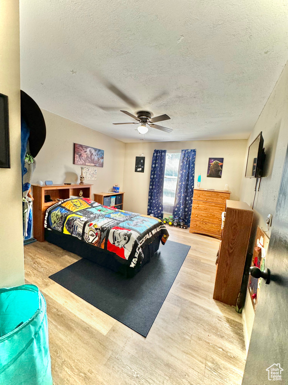 Bedroom with light hardwood / wood-style flooring, ceiling fan, and a textured ceiling