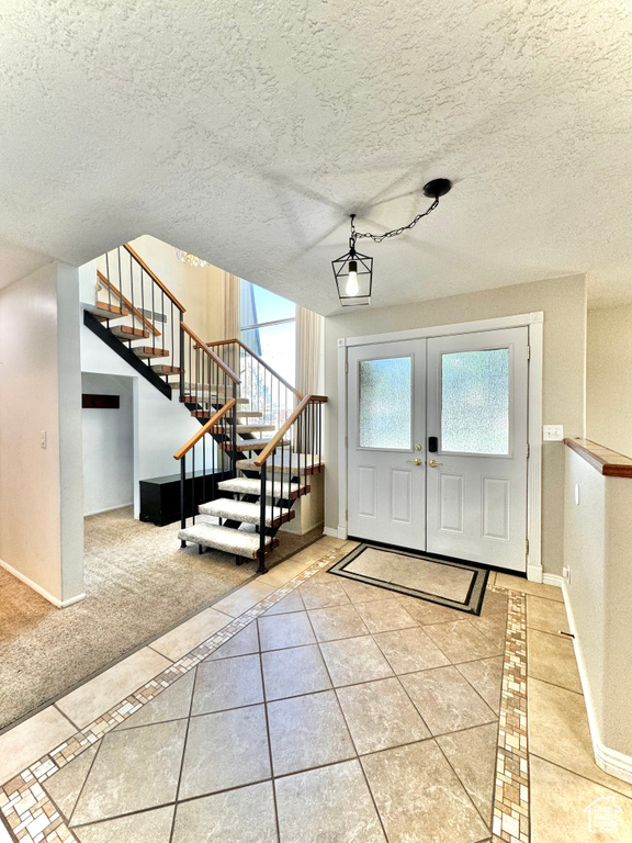 Entryway with carpet floors, a textured ceiling, and french doors