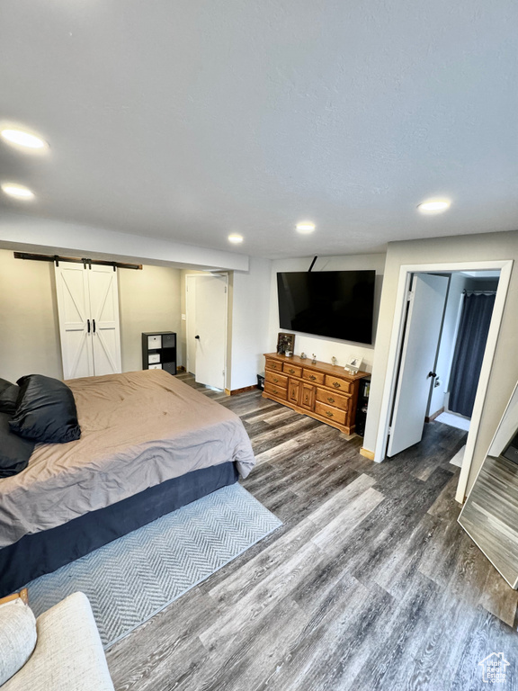 Bedroom featuring a barn door and dark hardwood / wood-style flooring