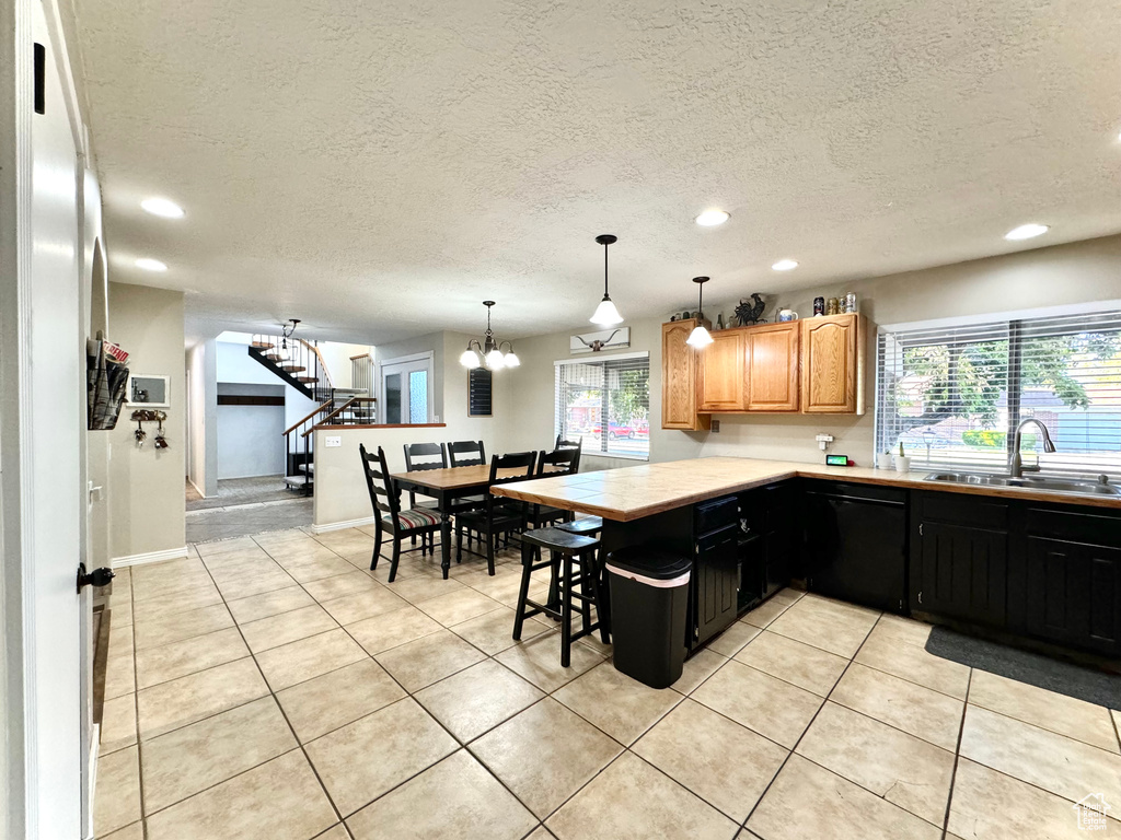 Kitchen featuring black dishwasher, light tile patterned flooring, sink, and a wealth of natural light